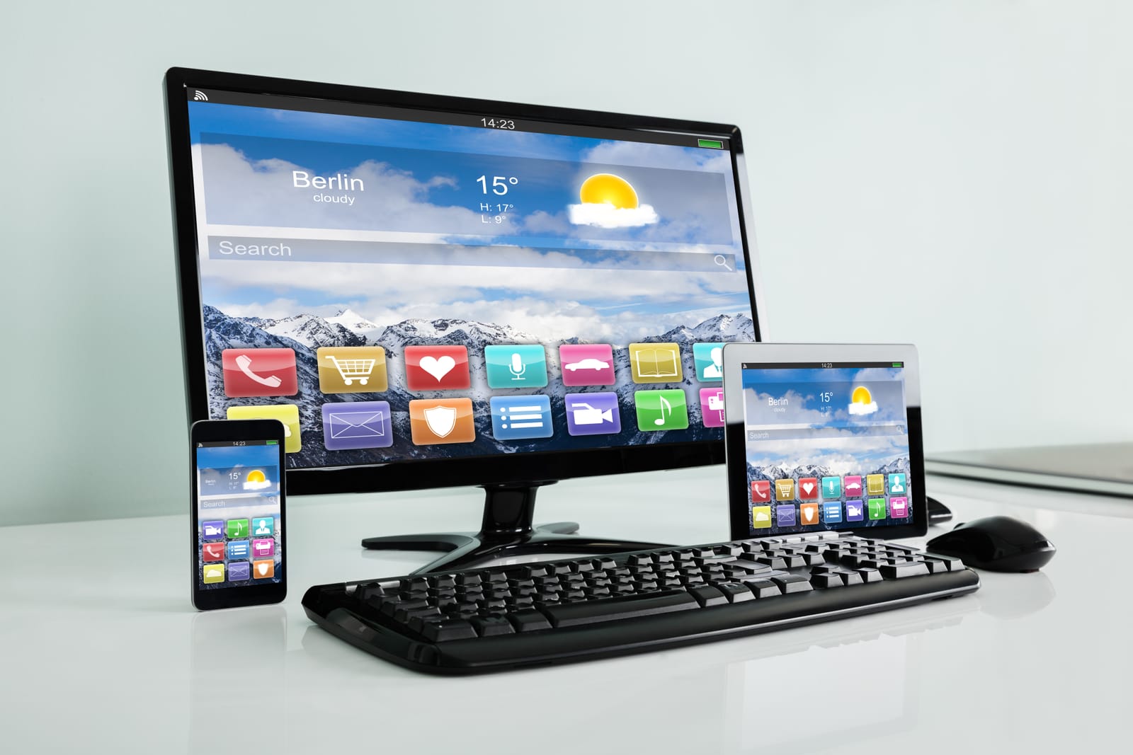 An office desk showing a desktop monitor, tablet, and smartphone, illustrating the choice between different devices in the laptop vs tablet debate.