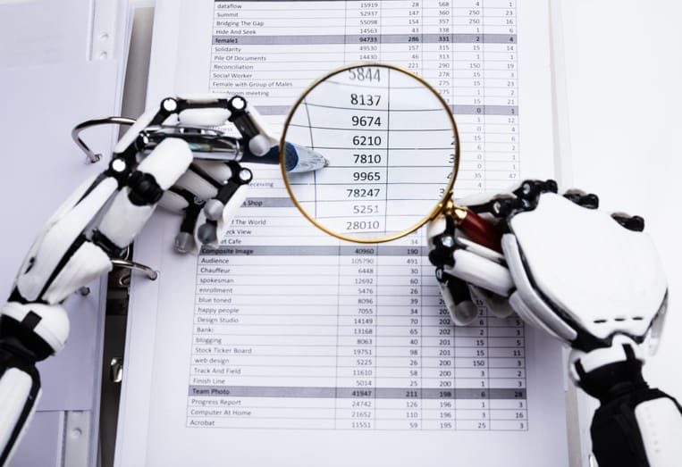 A robotic hand holds a magnifying glass over a spreadsheet, symbolizing the detailed analysis of the environmental and resource cost of artificial intelligence.