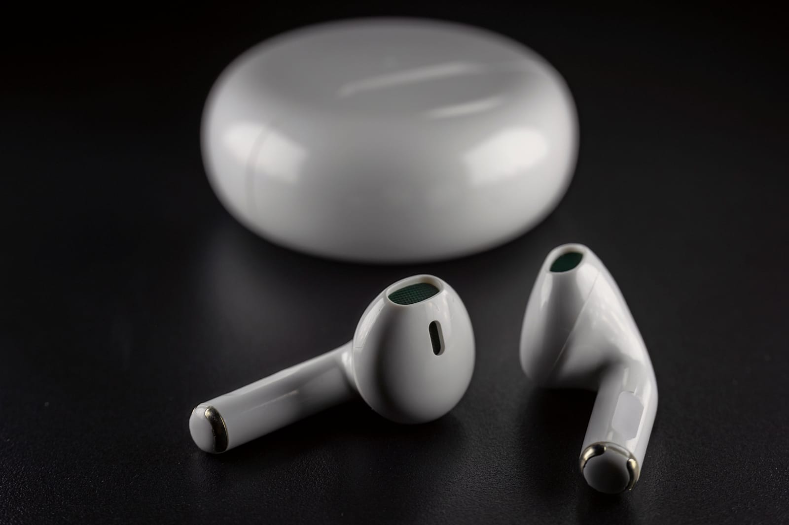 A pair of white wireless earbuds with their charging case, illustrating a key choice in the earbuds vs headphones comparison.